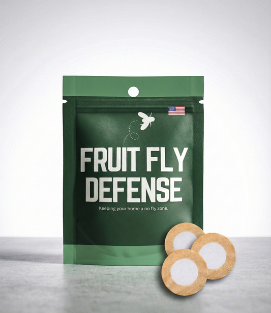 Green package labeled 'Fruit Fly Defense' with two round wooden tablets on a gray surface. Industry leading fruit fly deterrent meant for homes, kitchens, commercial applications.